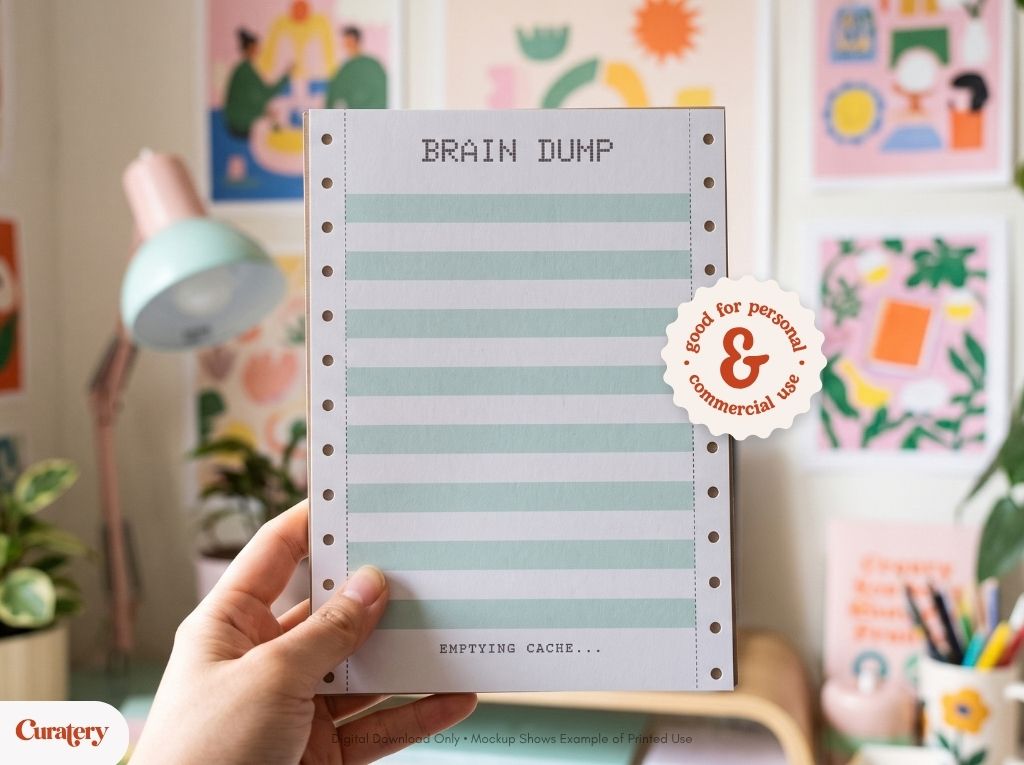 A hand holds a notepad with "BRAIN DUMP" at the top, light green and white stripes, and "EMPTYING CACHE..." at the bottom, featuring perforated edges and a circular sticker that reads "good for personal & commercial use."