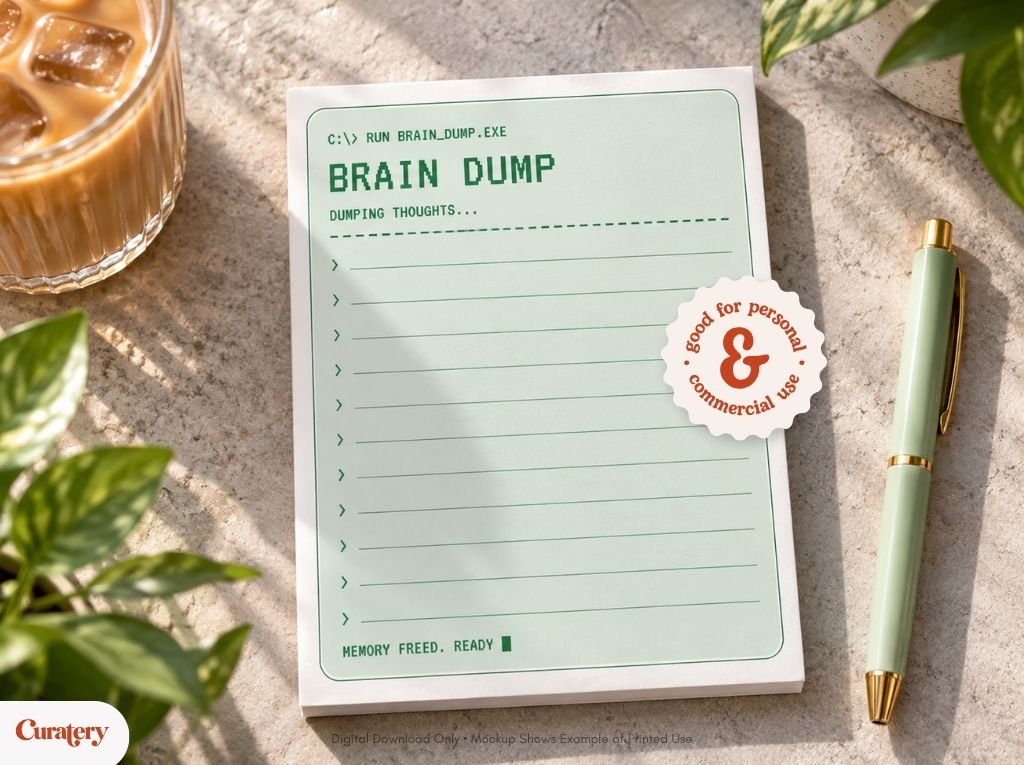A light green notepad designed to resemble a computer command-line interface displays "C:> RUN BRAIN_DUMP.EXE", "BRAIN DUMP", "DUMPING THOUGHTS...", and "MEMORY FREED. READY", along with a circular sticker stating "good for personal & commercial use", all resting on a textured surface with a drink and pen nearby.